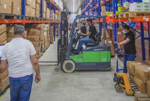Forklift operator moving stock through warehouse aisles
